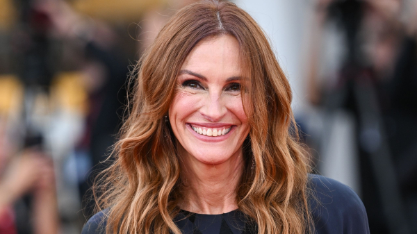 Julia Roberts smiles on the red carpet. She wears a navy dress and has her hair styled in waves.